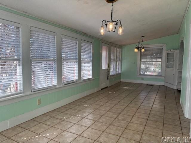 unfurnished dining area featuring light tile patterned flooring, baseboards, and a chandelier