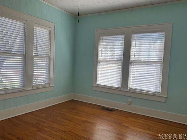 unfurnished room featuring visible vents, baseboards, wood finished floors, and crown molding