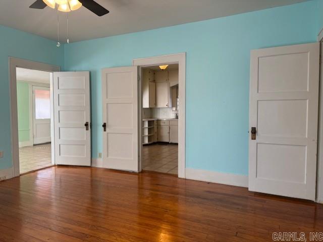 empty room featuring baseboards, wood finished floors, and a ceiling fan