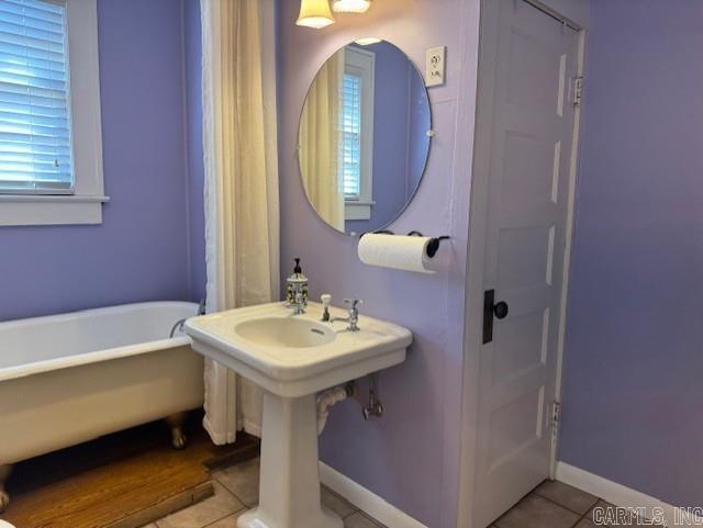 full bath with tile patterned flooring, a freestanding tub, and baseboards