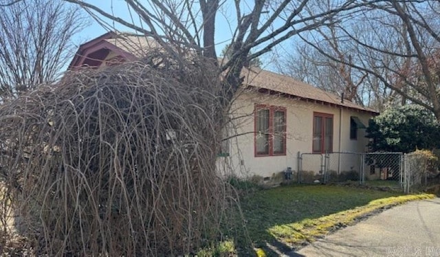 view of side of property featuring crawl space, stucco siding, a lawn, and fence