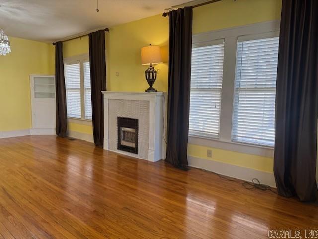 unfurnished living room with a fireplace, baseboards, and wood finished floors