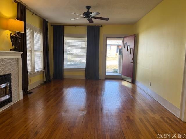 unfurnished living room with a ceiling fan, wood finished floors, a fireplace, and baseboards