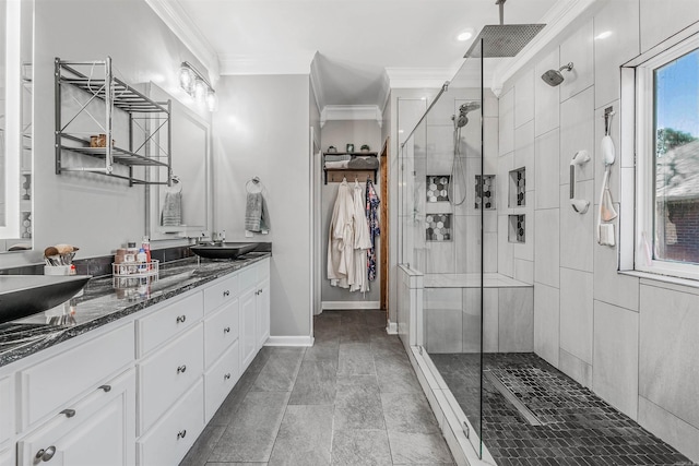 full bathroom featuring baseboards, double vanity, ornamental molding, a stall shower, and a sink