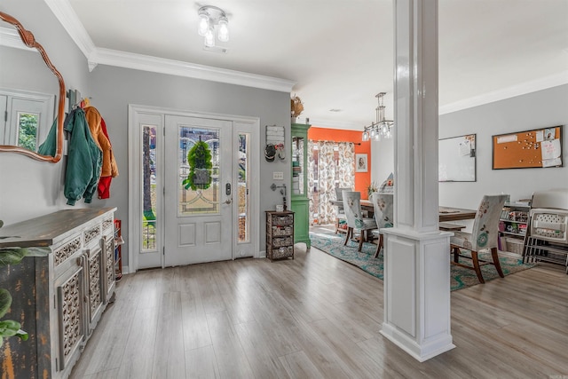 entrance foyer with crown molding, light wood-type flooring, and an inviting chandelier