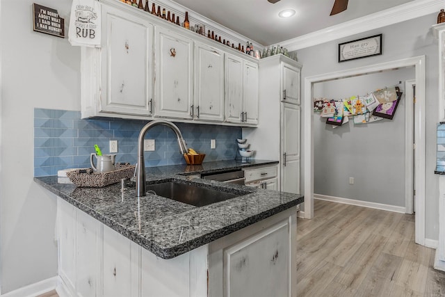 kitchen featuring a sink, light wood-style floors, backsplash, and white cabinets