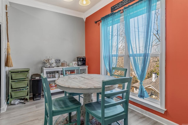 dining area featuring crown molding, light wood-type flooring, and baseboards