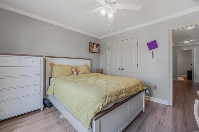 bedroom featuring ornamental molding, a ceiling fan, wood finished floors, a closet, and baseboards