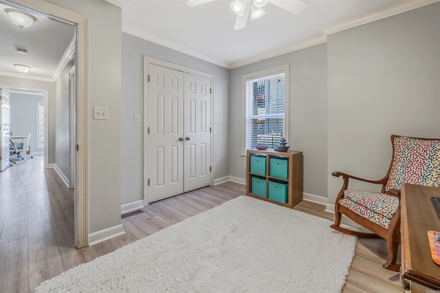 sitting room with visible vents, wood finished floors, baseboards, and ornamental molding