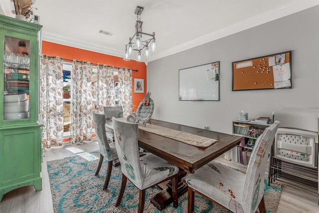 dining area with visible vents, a notable chandelier, wood finished floors, and crown molding