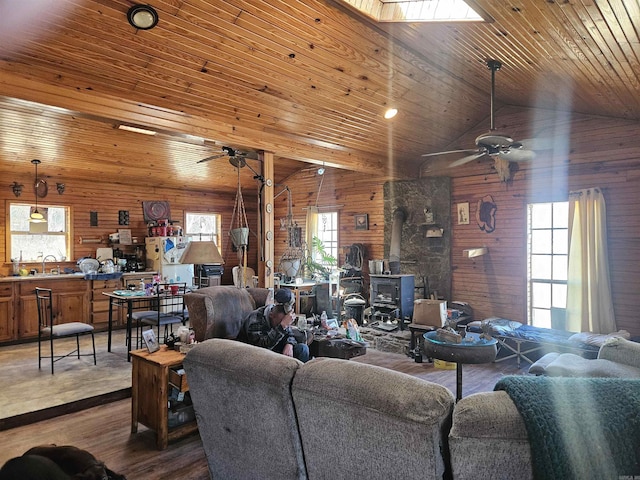 living area featuring wood walls, wooden ceiling, ceiling fan, and wood finished floors