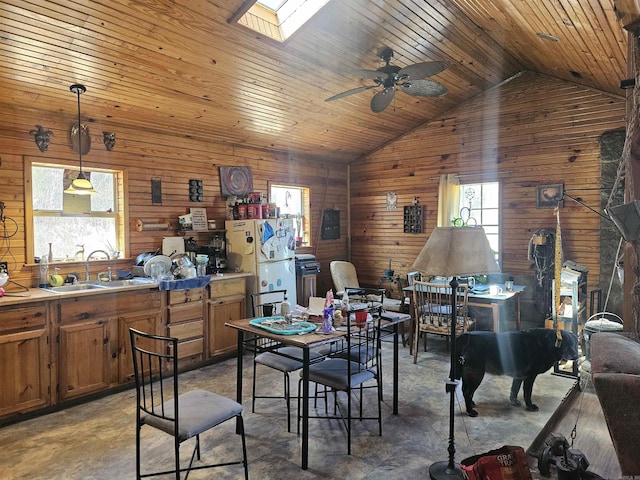 dining area with vaulted ceiling with skylight, wood walls, wooden ceiling, concrete flooring, and ceiling fan