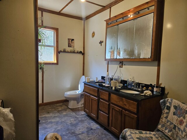 full bath with toilet, a sink, crown molding, double vanity, and baseboards