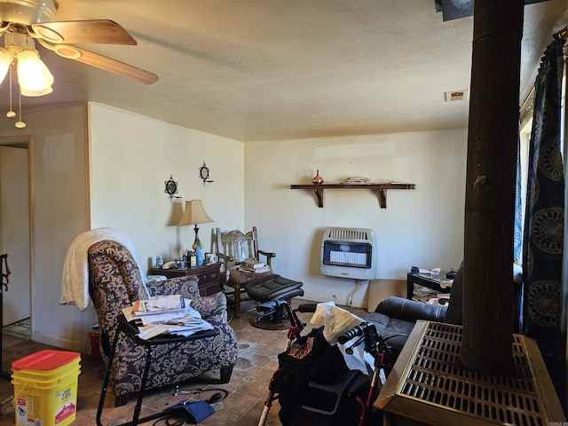 living area with visible vents, heating unit, a textured ceiling, and ceiling fan