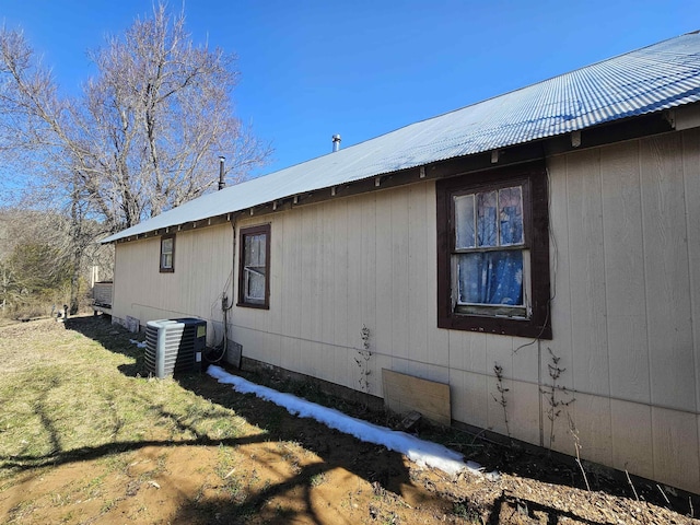 view of property exterior with cooling unit, a yard, and metal roof