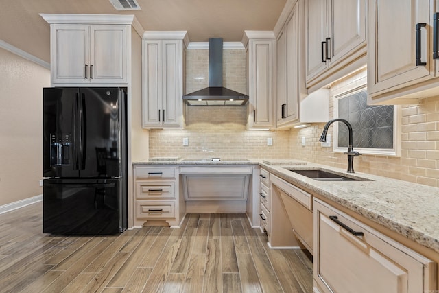 kitchen featuring a sink, black appliances, ornamental molding, and wall chimney range hood