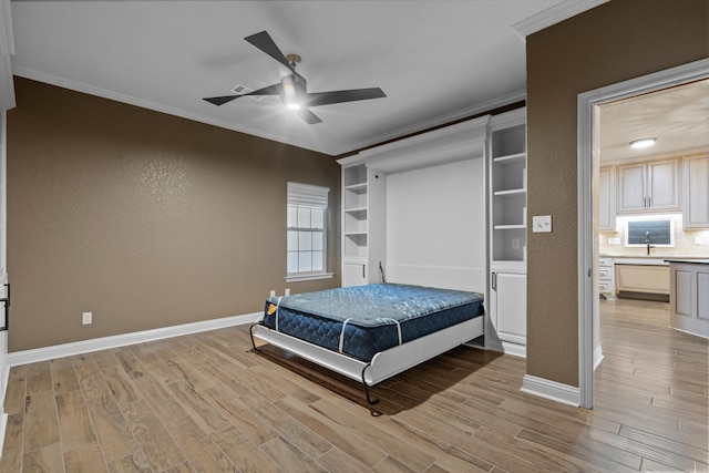 bedroom featuring baseboards, ceiling fan, crown molding, and light wood finished floors