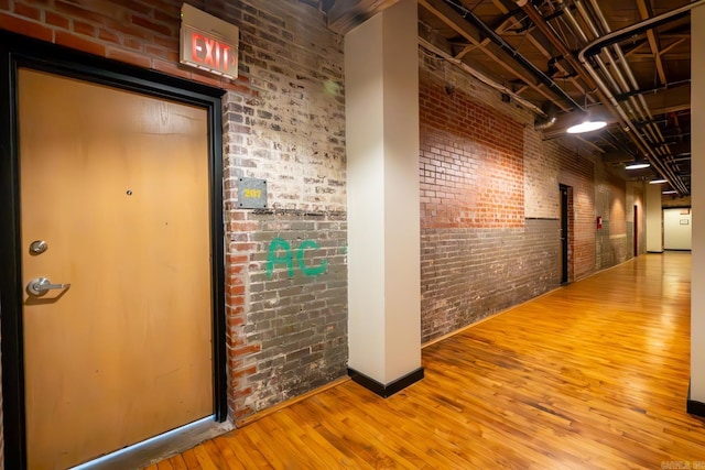 hallway featuring brick wall and hardwood / wood-style flooring