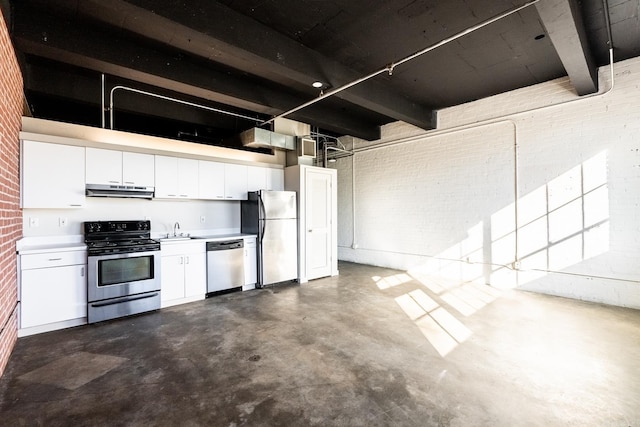 kitchen featuring brick wall, concrete floors, a sink, under cabinet range hood, and appliances with stainless steel finishes