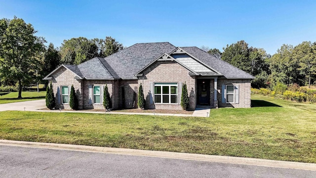 craftsman house featuring brick siding, a shingled roof, and a front lawn