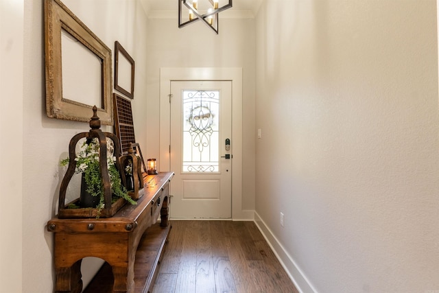 entryway featuring dark wood finished floors, a notable chandelier, crown molding, and baseboards