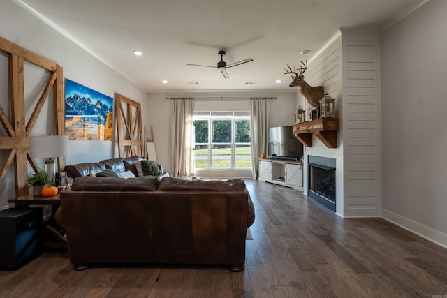 living room with ornamental molding, a ceiling fan, a fireplace, baseboards, and dark wood-style flooring