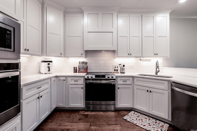 kitchen with dark wood-style flooring, a sink, decorative backsplash, light countertops, and appliances with stainless steel finishes