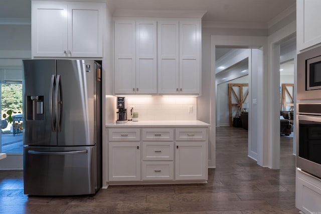 kitchen featuring dark wood-type flooring, tasteful backsplash, appliances with stainless steel finishes, white cabinets, and crown molding