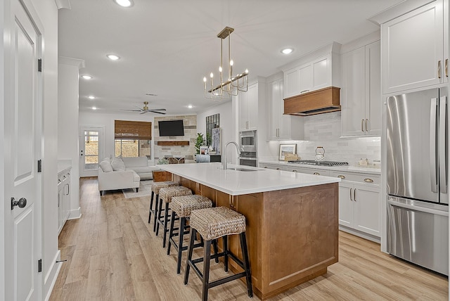 kitchen with light countertops, light wood-type flooring, open floor plan, and stainless steel appliances