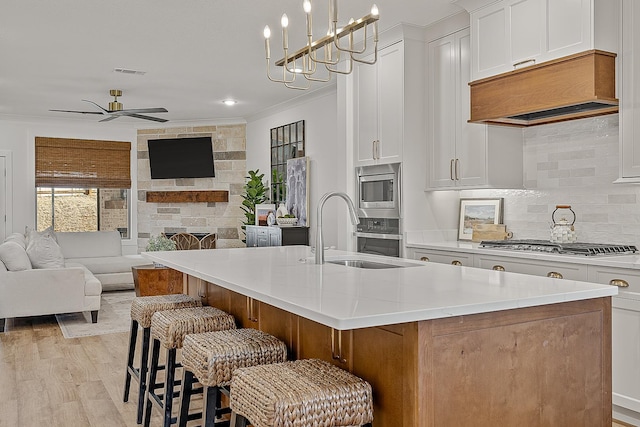 kitchen with visible vents, open floor plan, ornamental molding, appliances with stainless steel finishes, and a sink