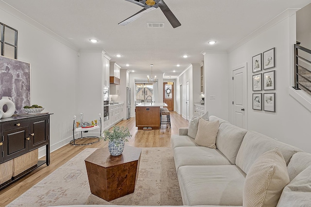 living area with visible vents, ornamental molding, ceiling fan with notable chandelier, recessed lighting, and light wood finished floors