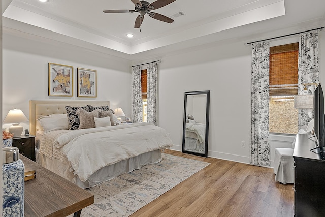 bedroom with light wood finished floors, visible vents, baseboards, recessed lighting, and a raised ceiling