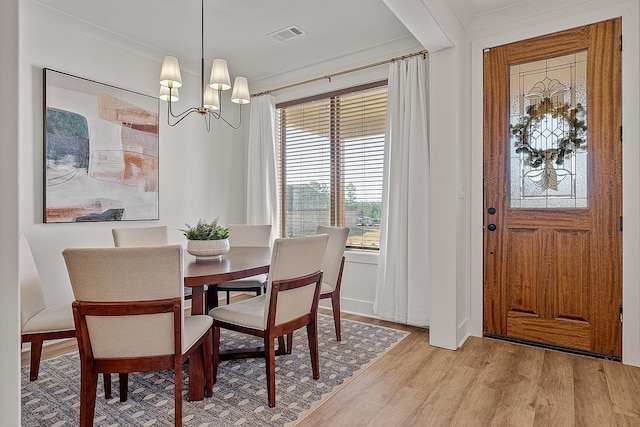 dining space with light wood finished floors, a notable chandelier, and ornamental molding