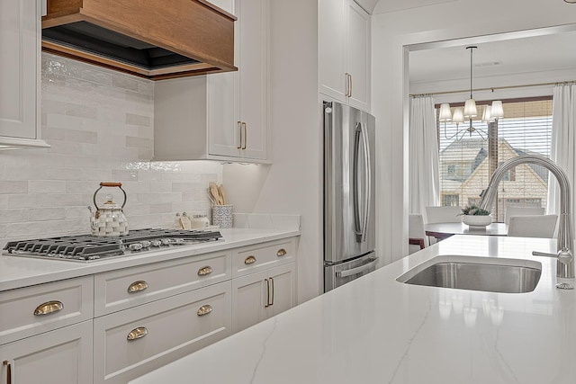 kitchen featuring a sink, custom range hood, white cabinets, appliances with stainless steel finishes, and tasteful backsplash