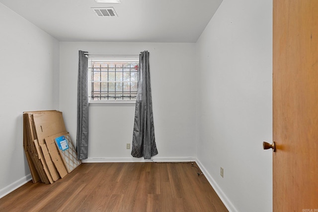 unfurnished room featuring visible vents, baseboards, and wood finished floors