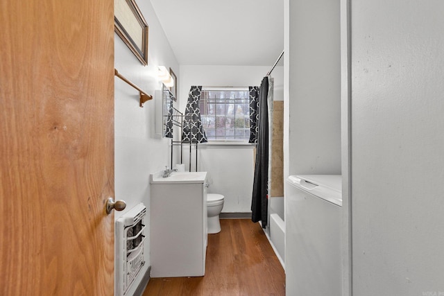 bathroom with vanity, heating unit, wood finished floors, curtained shower, and toilet