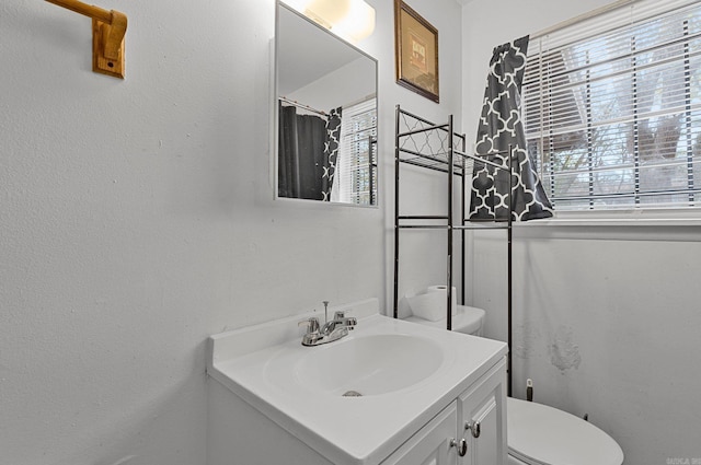 full bath with plenty of natural light, toilet, and vanity