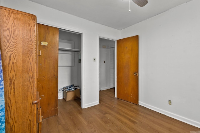 unfurnished bedroom featuring a closet, a ceiling fan, baseboards, and wood finished floors