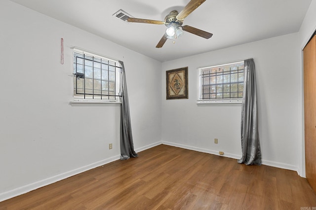 empty room with ceiling fan, baseboards, plenty of natural light, and wood finished floors