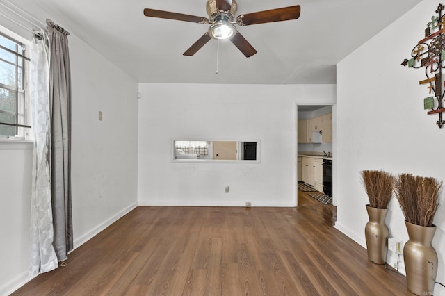 unfurnished living room with dark wood-style floors, a ceiling fan, and baseboards