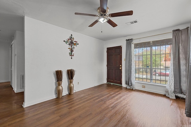 empty room featuring wood finished floors, visible vents, and baseboards