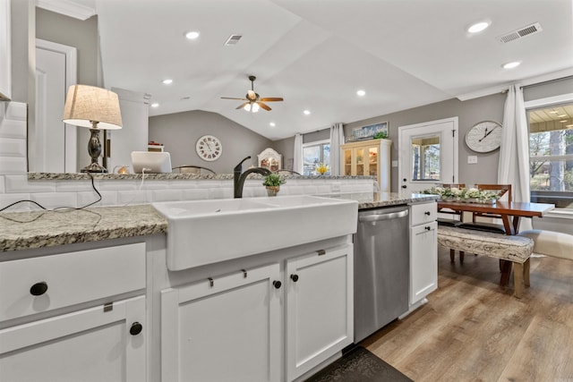 kitchen with visible vents, a sink, vaulted ceiling, stainless steel dishwasher, and light wood-type flooring