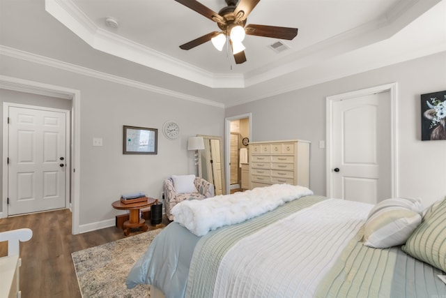 bedroom with visible vents, a raised ceiling, wood finished floors, crown molding, and baseboards