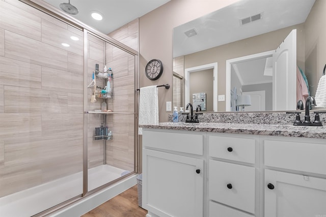 bathroom featuring visible vents, a stall shower, wood finished floors, and double vanity