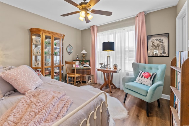 bedroom with a ceiling fan, wood finished floors, and baseboards