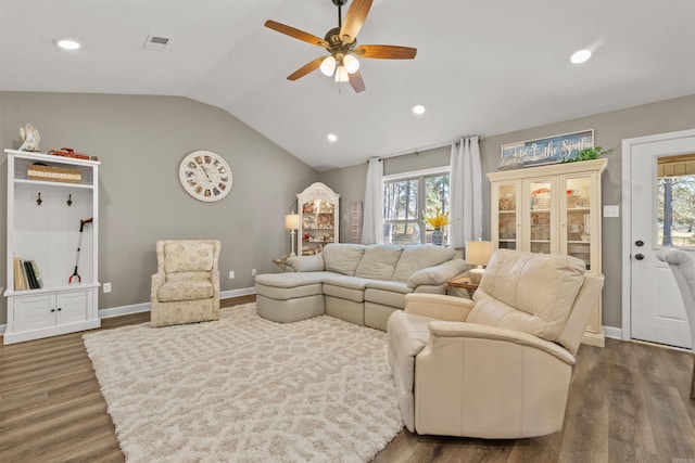 living area with lofted ceiling, wood finished floors, visible vents, and baseboards