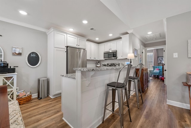 kitchen with visible vents, white cabinetry, appliances with stainless steel finishes, a peninsula, and light stone countertops