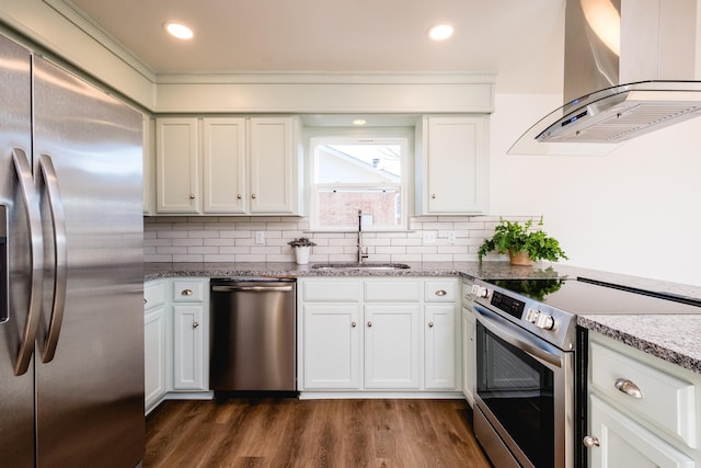 kitchen featuring tasteful backsplash, a sink, wall chimney range hood, appliances with stainless steel finishes, and dark wood-style flooring