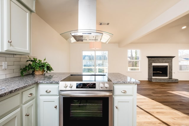 kitchen with stainless steel electric range oven, a peninsula, open floor plan, tasteful backsplash, and island range hood