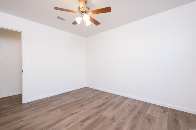 empty room with ceiling fan, visible vents, baseboards, and wood finished floors